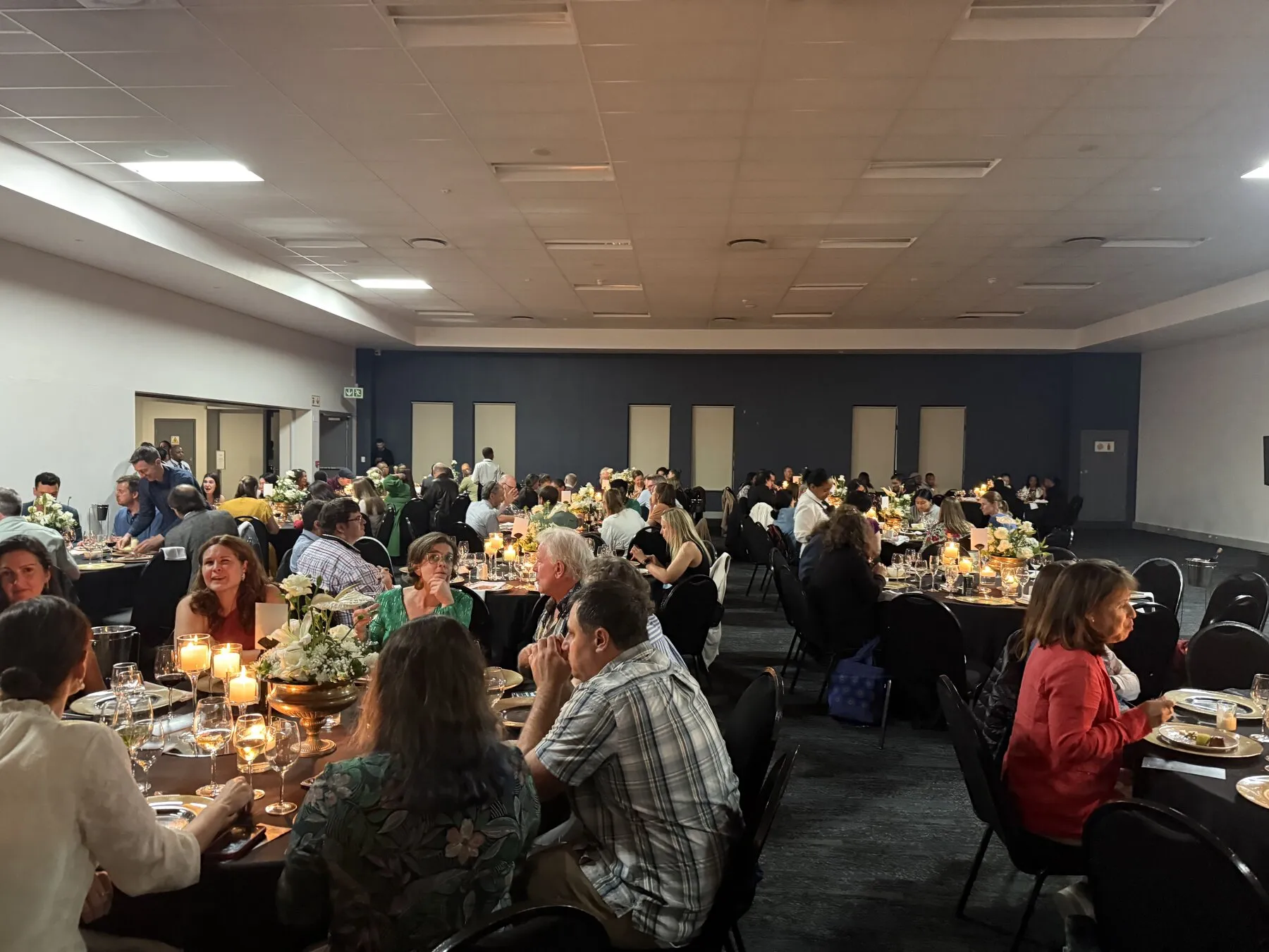 Conference attendees seated around tables at an evening dinner