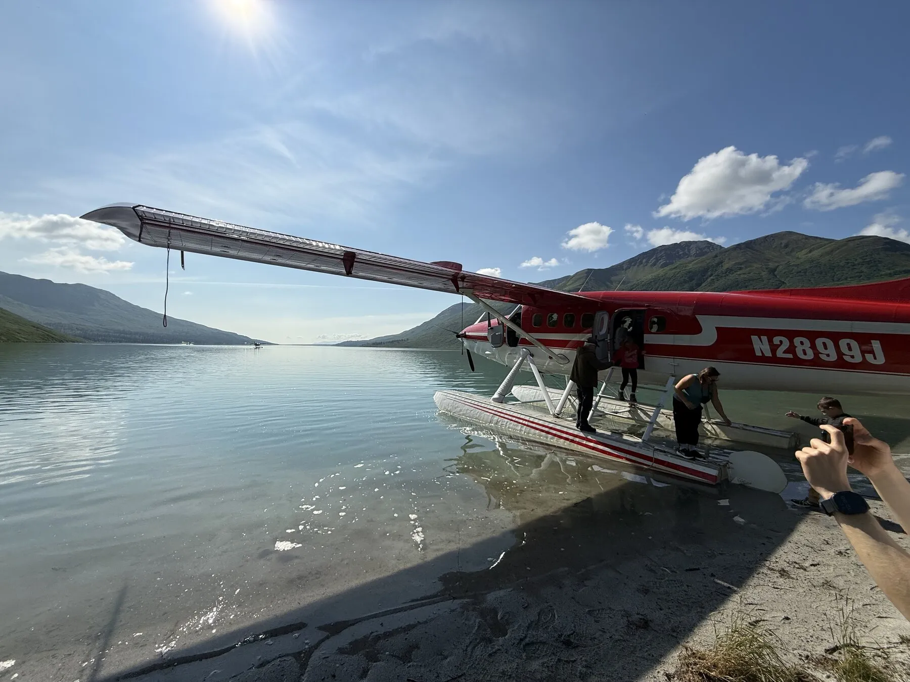 A red floatplane beside the shore of a mountain lake