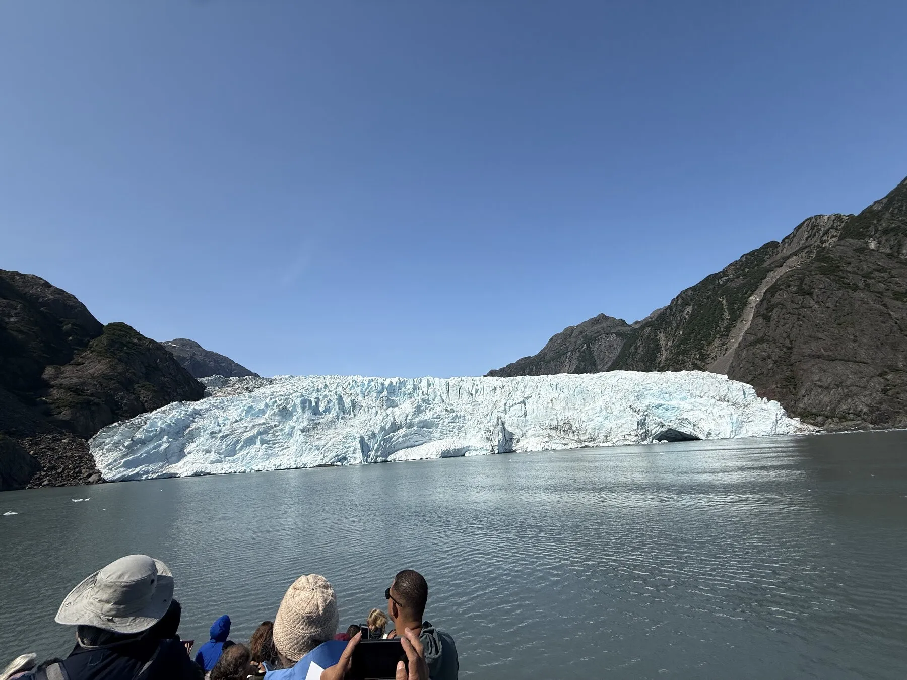 Passengers on the boat looking toward a glacier meeting the water