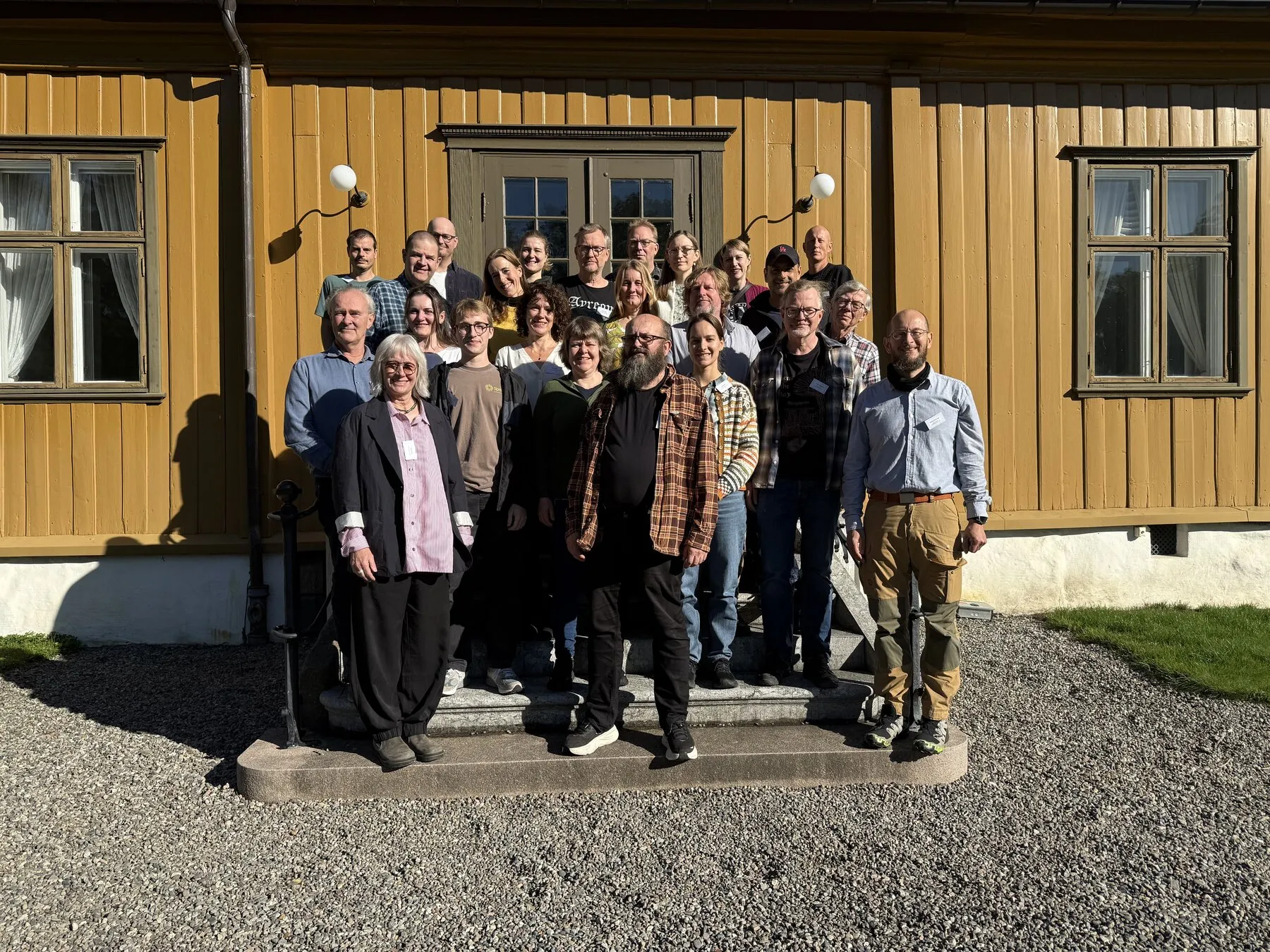 Workshop participants gathered outside a yellow wooden building in Oslo