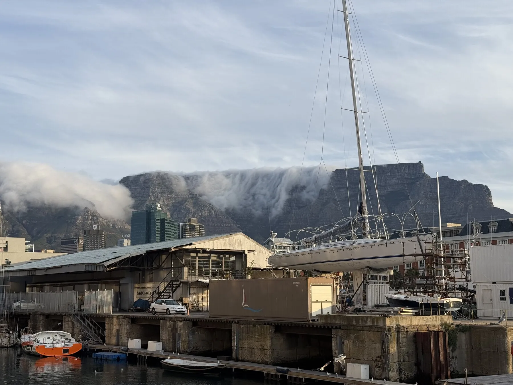 Boats at the Cape Town waterfront with clouds spilling over the mountain behind them